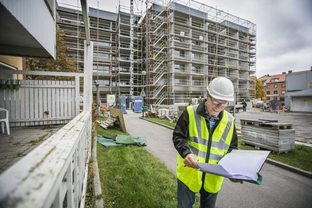 Encouraging residents to recycle. An environmental educationalist in high vis looks smiling at paperwork outside a housing development.